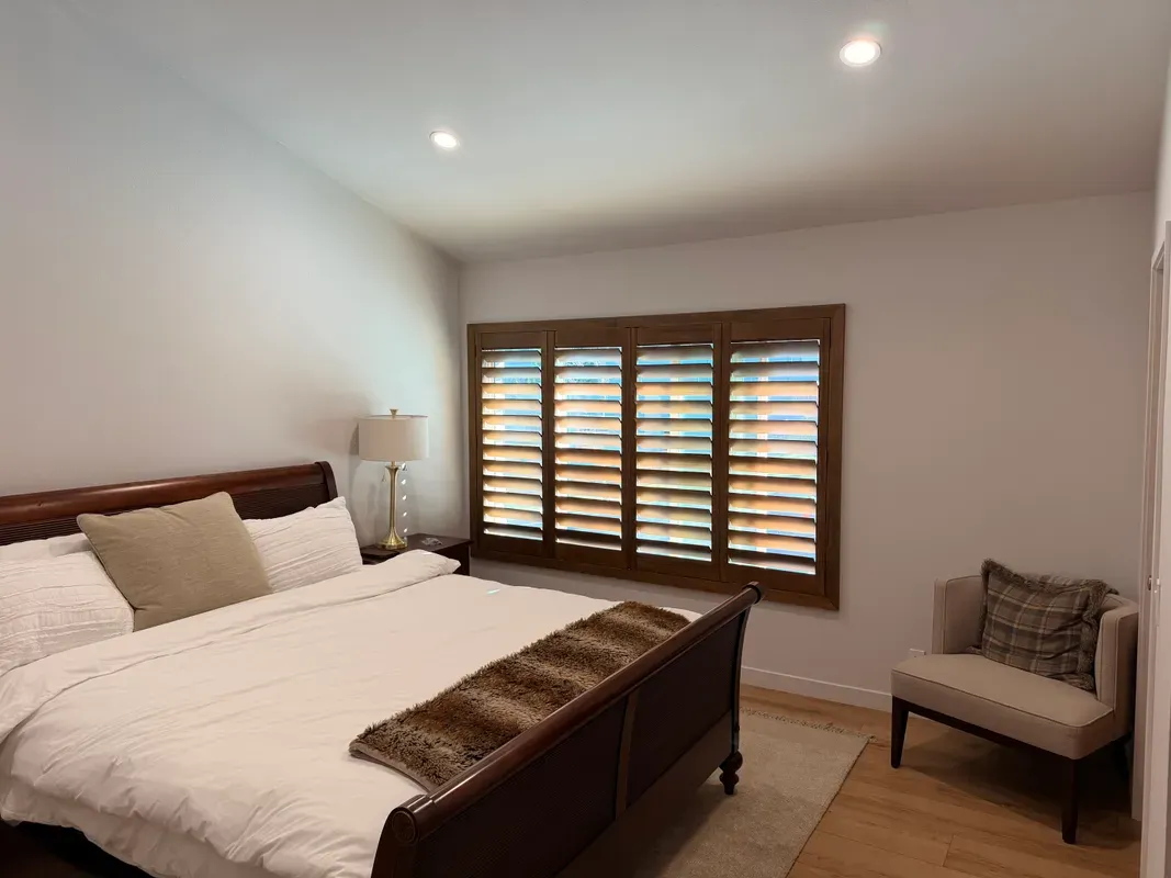Stained wood plantation shutters in a bedroom